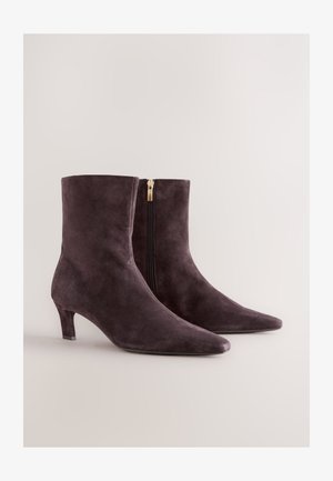 Tumesinised lamedapõhjalised saabastelikkadega paeltega, terava varbaga ja tagasihoidliku kannaga. Tagaküljel on kuldne lukk lihtsamaks jalga panekuks.