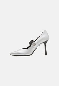 Pantof înalt din piele argintie, cu vârf ascuțit, accent cu curea neagră și finisaj lucios, având o siluetă elegantă și toc subțire.