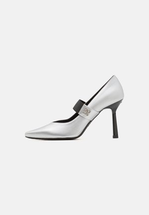 Sudraba ādas augstpapēžu kurpe ar saplacinātu purngalu, melnu siksniņu akcentu un spīdīgu apdari, piedāvājot elegantu siluetu un plānu papēdi.