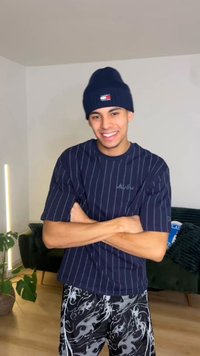 Námořnicky pruhované tričko s logem "New Era" v kombinaci s černými šortkami s plamenným vzorem. Na hlavě tmavá pletená čepice.