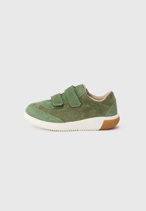 Grønn mockaskinn sneaker med to justerbare borrelåsremmer, myk beige fôr og en hvit gummisål med teksturert grep.