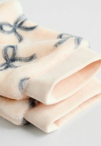 Faux-Fur-Stoff in sanftem Pfirsichfarben, mit dunkelgrauen Schleifenmustern. Die Bündchen sind mit einer gerippten Textur gestrickt.