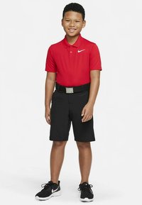 Rdeča polo majica s ovratnikom, črne kratke hlače, črni pas s srebrno sponko in črni športni copati. Preprost dizajn, primeren za vsakdanje nošenje.