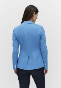 Ljusblå blazer med en strukturerad design, slagkrage och en enda ventil bak; har knäppte ärmar och skräddarsydd passform.