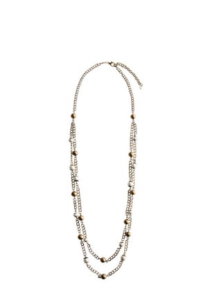 Long collier chaîne en or à double couche avec des grosses perles rondes dorées et blanches alternées sur fond blanc.