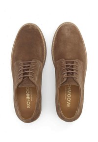 Chaussures en suède marron avec un design à lacets, bout rond et semelle en caoutchouc beige. L'intérieur présente un marquage doré et le texte "Fabriqué au Portugal".