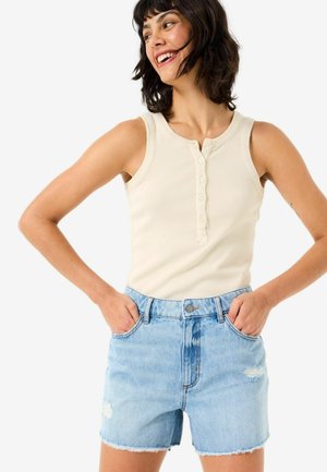 Helles beige, geripptes Tanktop mit Knöpfen und hellblauen Denim-Shorts, die einen ausgefranseten Saum und abgenutzte Akzente aufweisen und eine taillierte Passform präsentieren.