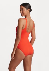 Klarröd baddräkt med låg rygg och breda justerbara axelband, tillverkad av mjukt, elastiskt material. Minimalistisk design utan mönster.