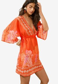 Svijetlo narančasti kaftan s V-izrezom i širokim rukavima, s cvjetnim uzorcima u ružičastoj boji. Uključuje vezanje u struku i ukrasne detalje na rubu.