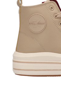Zapatilla alta beige con parte superior de imitación de piel texturizada, detalle de logo redondeado, costuras tono sobre tono y suela de plataforma crema.