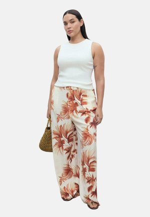 White, sleeveless top paired with wide-leg pants featuring a tropical orange floral pattern; model holding a woven handbag.