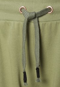 Olijf groene sweats met een geribde tailleband en een gevlochten trekkoord in dezelfde kleur, voorzien van zwarte uiteinden.