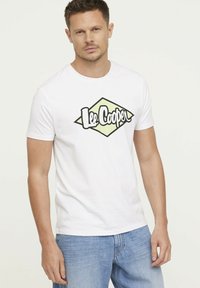 Witte katoenen t-shirt met een zwart en lichtgroen "Lee Cooper" logo in diamantvorm in het midden. Korte mouwen, ronde halsontwerp.