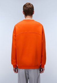 Felpa arancione con scollo rotondo, maniche lunghe e vestibilità rilassata. Tessuto liscio con un dettaglio cucito sulla parte posteriore.