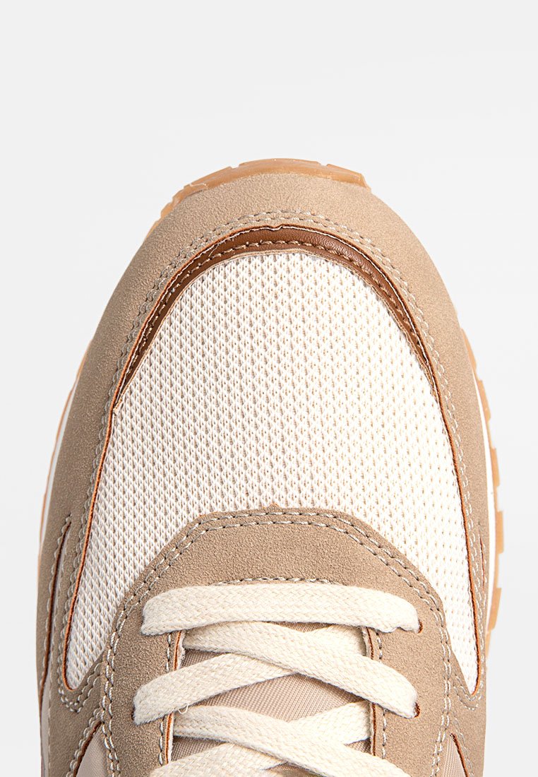Lichtbruine suède en beige mesh sneaker met crèmekleurige veters, voorzien van een textuur op de neus en een versterkte bruine leren accent langs de rand.