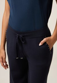 Marine joggingsbroek van zachte stof, met een trekkoord in de taille, zijzakken en decoratieve zilveren studs langs de zakken.