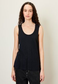 Tamsiai mėlyna bevardė palaidinė, pagaminta iš minkštos medžiagos su apvaliu kaklu ir plačiomis petnešomis. Laidūs išmatavimai, pritaikyti komfortui.