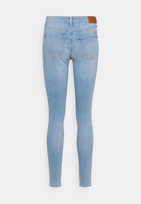 Vaqueros pitillo azul claro hechos de mezclilla, con cintura alta, dos bolsillos traseros y una etiqueta de cuero con la marca en la cintura.