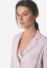 Licht paarse en witte gestreepte pyjama-top met een reverskraag, zak en knoopsluiting; gemaakt van zachte stof, casual ontwerp.