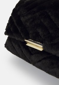 Crna clutch torbica od umjetnog krzna s kvadratnim uzorkom i zlatnim hardverom s ugraviranim tekstom "ARMANI EXCHANGE".