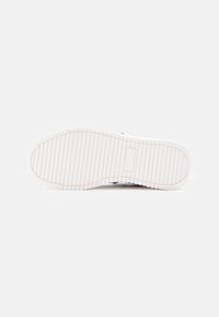 Baltas guminis batų padas su tekstūruotu, juostuotu raštu, užtikrinančiu sukibimą. Padas plokščias, su apvaliu pirštu, viduryje yra centrinis prekės ženklo akcentas.