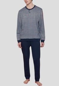 Top a maniche lunghe a scacchi in rosso, blu e bianco, abbinato a pantaloni blu navy. Il top presenta un collo tondo e polsini a coste.