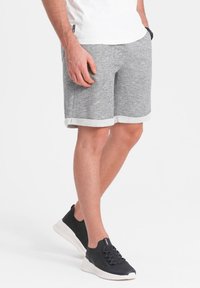 Šedé bavlněné šortky s texturovaným povrchem, s bílým lemem a bočními kapsami, doplněné černými slip-on teniskami.
