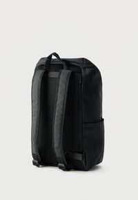 Μαύρο σακίδιο με λείο εξωτερικό, ιμάντες από δίχτυ για αερισμό, πλαϊνή τσέπη και ανθεκτική πάνω λαβή για εύκολη μεταφορά.