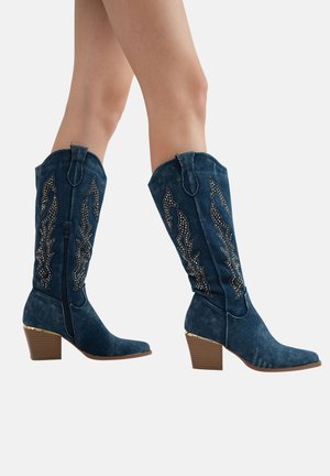 Botas vaqueras de denim con adornos decorativos de plata, punta afilada, tacón medio en bloque y elementos de diseño de estilo western.