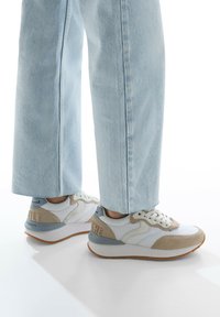 Sneakers in white and beige with light grey accents, featuring a textured finish, contrasting materials, and a rubber outsole.