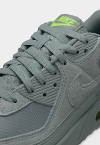 Baskets grises en mélange de suède et de mesh. Dotées de lacets plats, d'un panneau latéral texturé et d'un logo vert citron sur la langue.