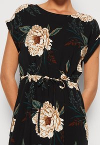 Czarna sukienka z dużymi beżowymi i brązowymi wzorami kwiatowymi, krótkimi rękawami, okrągłym dekoltem oraz regulowanym paskiem w talii.