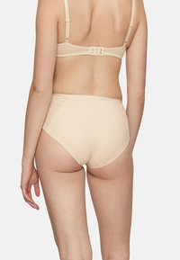 Beżowa, wysokowysoka bielizna z koronkowymi akcentami i gładką, elastyczną teksturą. Widok od tyłu pokazuje bezpieczny pas z zapięciem na haczyk.