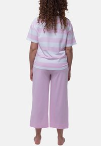 Helles rosa und weiß gestreiftes kurzärmliges Hemd kombiniert mit einfarbigen, rosa weiten Hosen aus weichem, atmungsaktivem Material.
