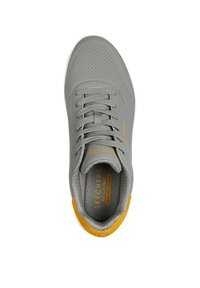 Grijze sport schoen met geperforeerde bovenkant, veters en gele accenten. Beschikt over een gevoerde binnenzool gemarkeerd met "Memory Foam" die ontworpen is voor comfort.