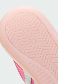 Potplat ružičaste tenisice s teksturiranim uzorkom riblje kosti, izrađen od poluprozirnog ružičastog materijala s utisnutim logotipom u sredini.