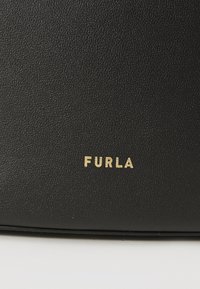 Musta nahkabag, jossa on teksturoitu pinta. Esittelyssä kultainen "FURLA"-logo näkyvissä. Yksinkertainen, suorakulmainen muotoilu.