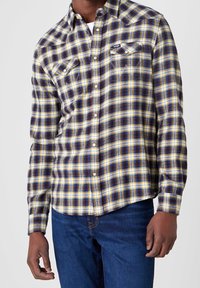 Geruite button-up shirt met een patroon in geel, marineblauw en bordeauxrood, twee borstzakken en een yoke-ontwerp in westernstijl.