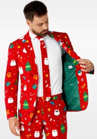 Costume rouge orné de motifs sur le thème de Noël, comprenant des visages de Santa, des sapins et des ornements. L'intérieur présente une doublure verte.
