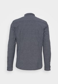 Camisa de hombre de manga larga en tela gris oscuro, con cuello abotonado, dobladillo recto y detalle de puño con un botón.
