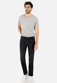 Dunkelblau Jeans kombiniert mit einem grauen Rundhals-T-Shirt und weißen Sneakern, mit einer lockeren Passform und vorderen Taschen.