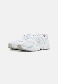 Un paio di scarpe da ginnastica bianche e azzurro chiaro con pannelli in rete, design con lacci e suole in gomma grigia su uno sfondo neutro.