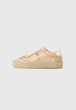Beige sneakers sima anyaggal, fehér részletekkel és szőtt jutaszóléval. Kerek logó részlet van az oldalon és fűzős kialakítást kapott.
