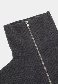 Col montant en maille côtelée gris foncé avec une fermeture éclair en métal argenté courant verticalement au centre.