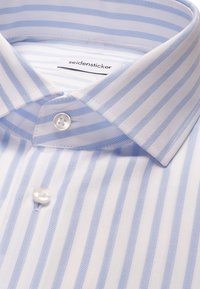 Chemise blanche avec des rayures verticales bleu clair, col boutonné et étiquette "seidensticker" à l'intérieur du col.