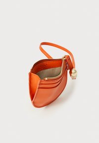 Orange leather pouch with a zip closure, curved shape, and a slim wrist strap. Features gold hardware and a textured surface.