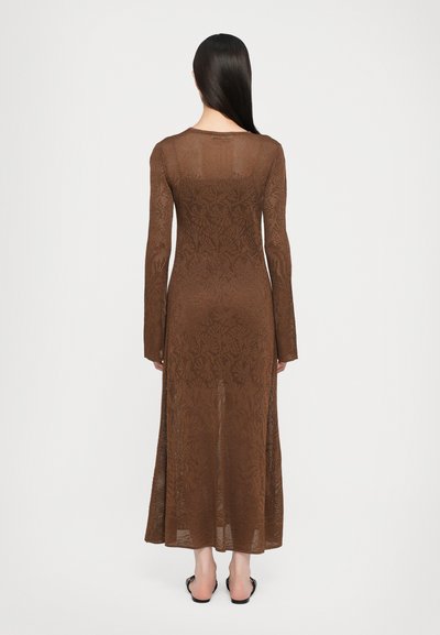 Bruine, gebreide maxi-jurk met lange mouwen, met een gestructureerd bloemenpatroon en een licht uitlopende silhouet. Open rugdetail.