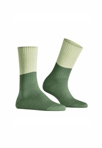 Zielone skarpetki o prążkowanej fakturze w dwóch odcieniach—jasnozielony mankiet i ciemnozielona cholewka. Miękka tekstura i klasyczna długość do kostki.