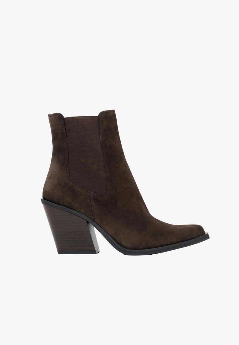 Ciemnobrązowy zamszowy botek za kostkę z zaostrzonym noskiem, elastycznymi panelami po bokach i grubym, warstwowym obcasem na białym tle.