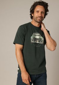Camiseta de algodón verde oscuro con un gráfico de un coche clásico, cuello redondo, mangas cortas y un corte relajado.
